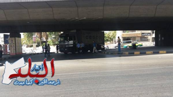 يالصور الآن.. شاحنة ضخمة تعلق اسفل جسر المدينة الرياضية ورجال السير يعملون على تحريكها