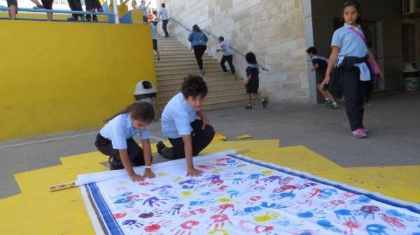 بالصور طلاب الفرير يخططون بأيديهم لوحة جدارية كبيرة تعبيرا عن السلام