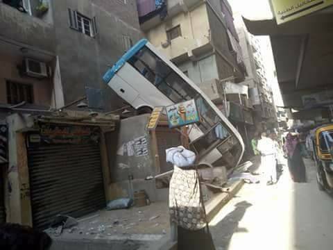 شاهد صور صادمة.. حافلة تسقط وتتعلق بركابها فوق مسكن من 6 طوابق بمصر