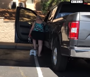 امرأة قصيرة تحل مشكلة صعودها السيارة بشكل طريف (فيديو)