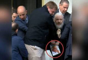 ما هو الكتاب الذي ظهر بيد مؤسس ويكيليكس لحظة اعتقاله؟