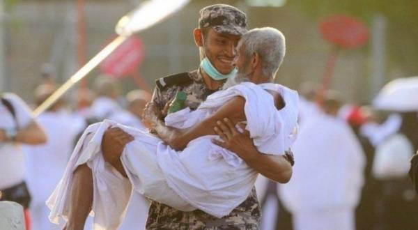 صورة تخطف الأنظار .. رجل أمن سعودي يحمل حاجاً نال منه التعب