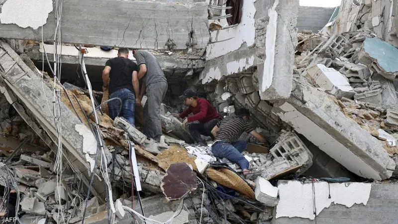 يقبل يدها تحت الأنقاض.. صحفي فلسطيني يقبل يد أحد ذويه من تحت ركام منزلهم الذي دمرته غارة إسرائيلية على قطاع غزة